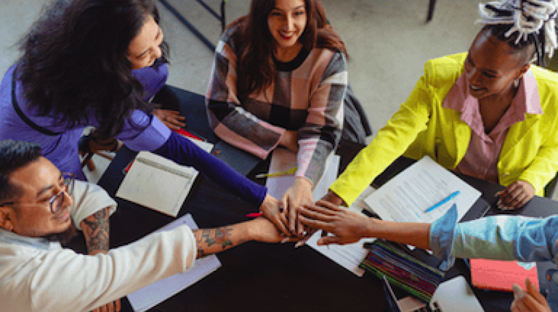 Group of people in office placing their hands together