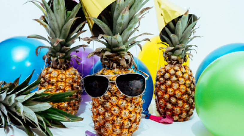 Several pineapples having a party, with sunglasses and balloons